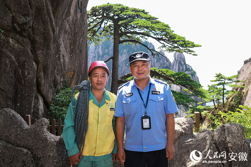 全国道德模范李培生（左）和胡晓春在迎客松前合影。人民网记者 张俊摄